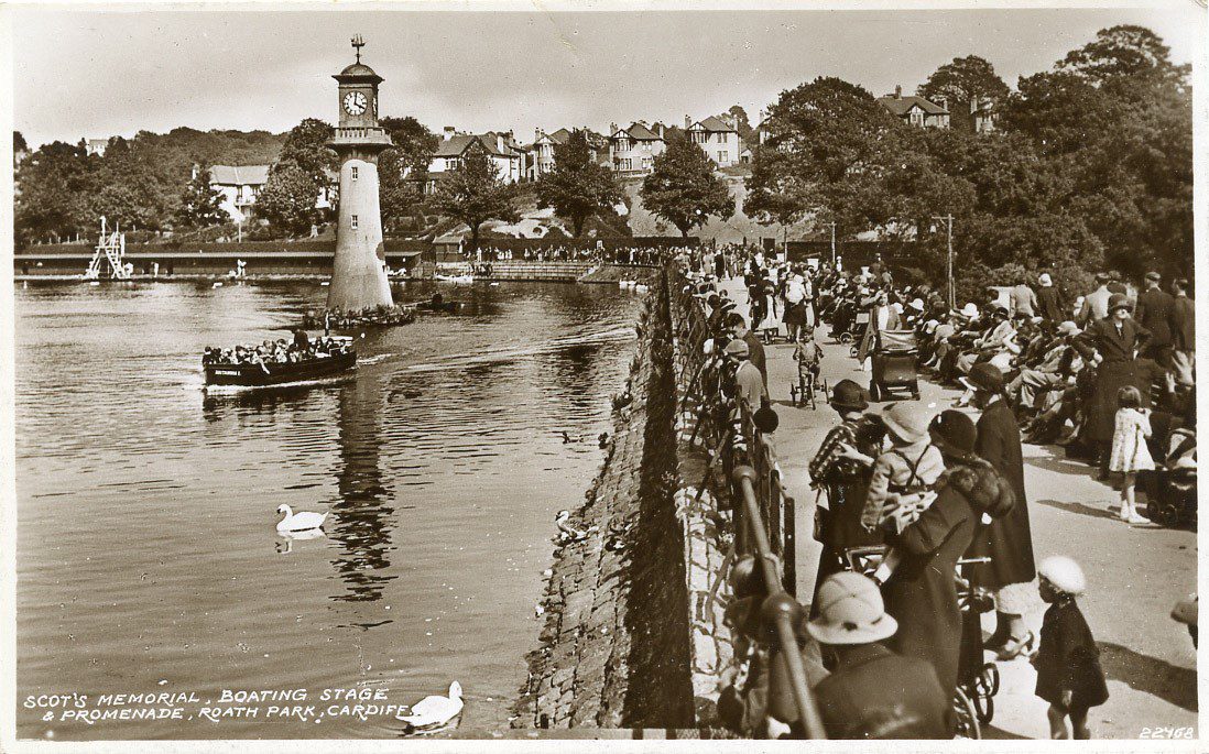 historic photo showing the promenade in Roath park with crowds of people watching boats on the lake
