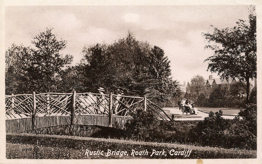 Historic postcard showing a rustic bridge crossing the brook in Roath park